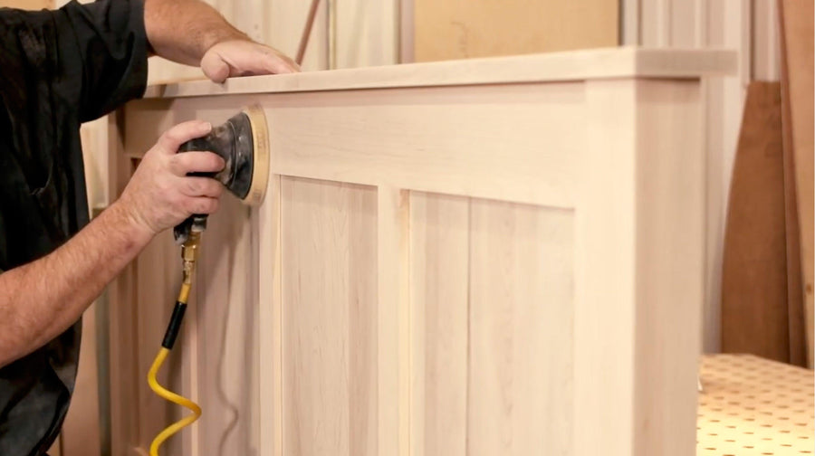 Amish craftsman sanding a hardwood bed headboard 