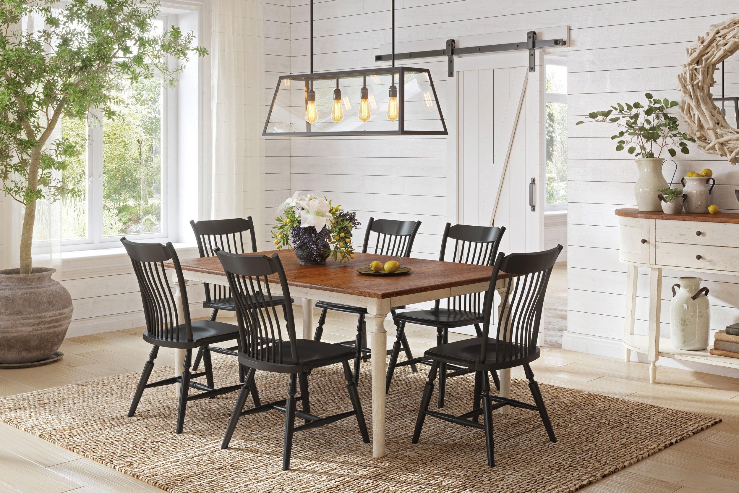 Crayton Amish Dining Collection featuring a Brown Maple dining table with an Almond stain top and Weathered Tusk stain base. The set includes six RH Yoder Crayton chairs in Black paint, all set in a bright and airy dining room with a rustic-modern aesthetic.